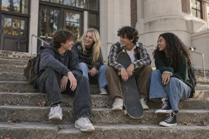 A group of teenagers laughing together on outdoor steps.